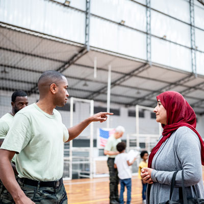 soldier speaking to a woman in a hijab