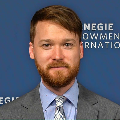 Jon Bateman in a suit and tie in front of a Carnegie Endowment background