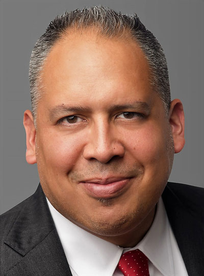 Brandon Valerino headshot in a suit and tie with a gray background