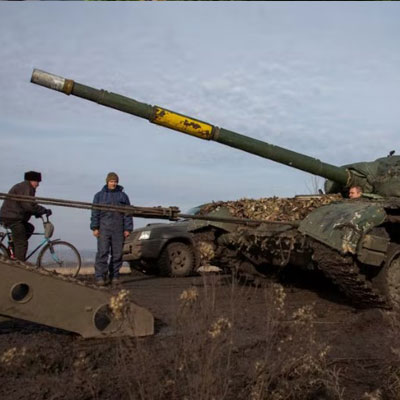 A broken tank is pulled to a truck near the frontline town of Bakhmut in Ukraine