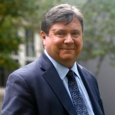 Headshot of Jim Walsh standing outside in a suit and tie