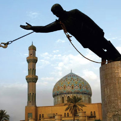 A statue of a man being pulled down off of its pedestal by a crane