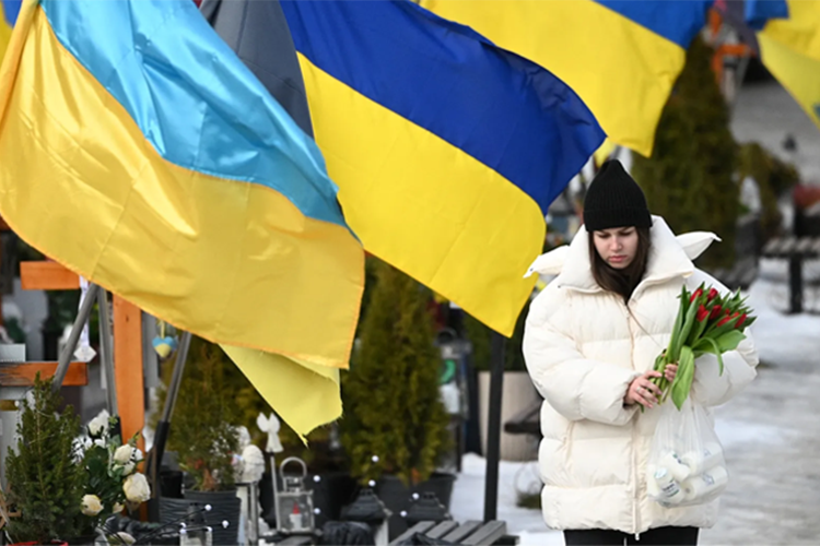 A mourner holds flowers on Valentine's Day at the Lychakiv Military Cemetery in Lviv, on February 14, 2026, amid the Russian invasion of Ukraine.