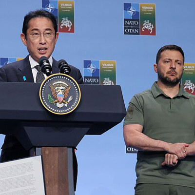 Fumio Kishida speaking at a podium with US President Biden and Ukrainian President Zelenskyy