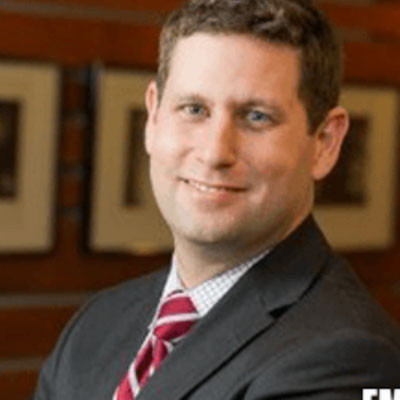 headshot of Russell Rumbaugh in a suit and tie