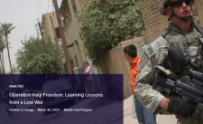 A soldier walking down a street near people in Iraq